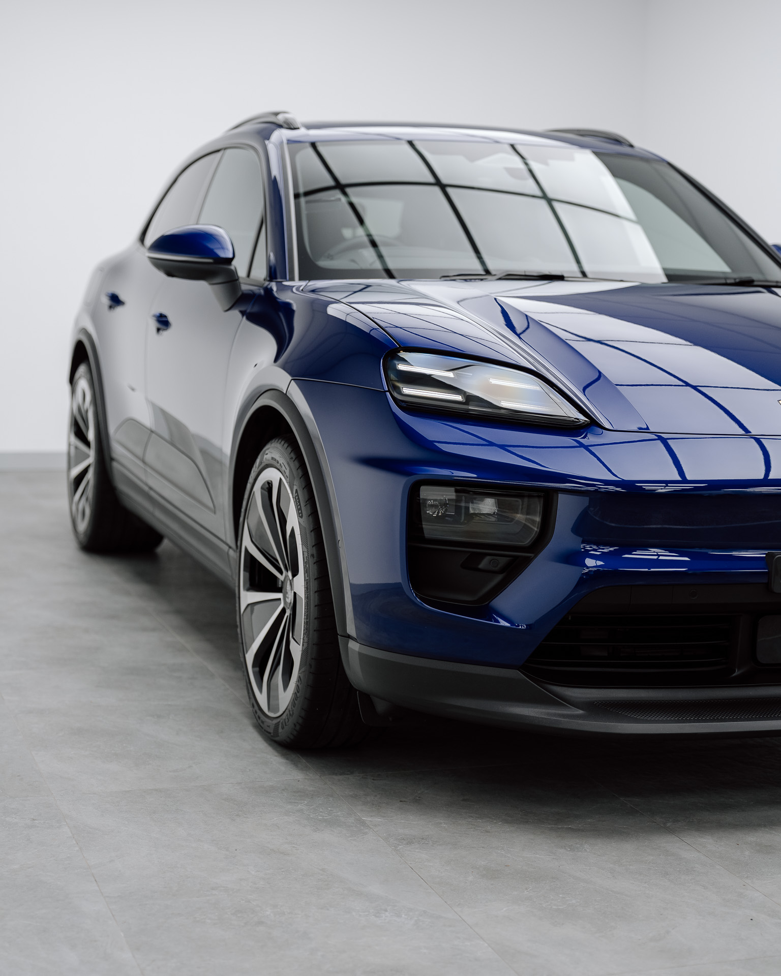 Blue Porsche Macan Electric front three-quarter view in a studio, protected by Defcon Films Australia gloss paint protection film
