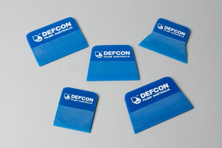 Five blue Defcon Films Australia squeegees on a grey background